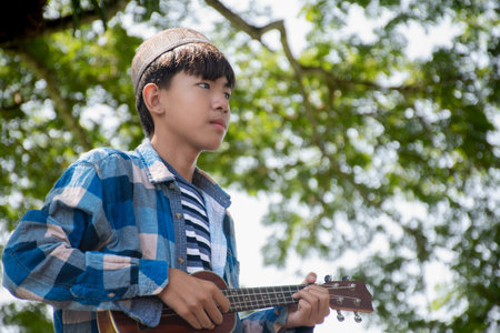 Young asian boy playing ukulele in the park.の写真素材