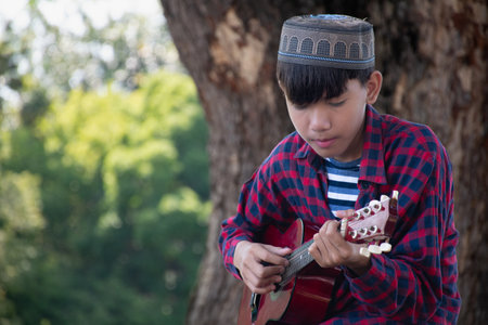 Young asian boy playing ukulele in the park.の写真素材