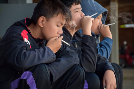 Unidentified Thai students are smoking a cigarette in the school.の写真素材