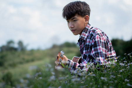 Little boy sitting on the daisy field and looking at the cameraの写真素材
