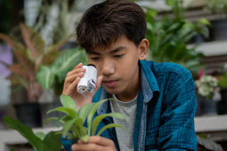 Asian boy sneezing in handkerchief with plant in pot.の写真素材