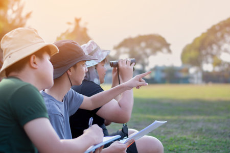 Asian preteens spending their freetimes and doing recreational activity by watching birds in late...