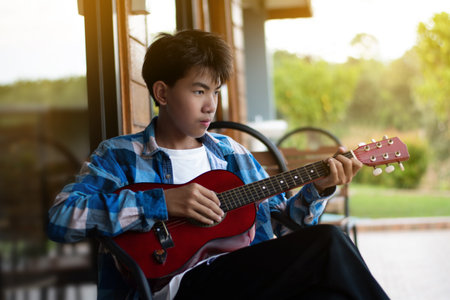 Young asian boy playing ukulele in the park.の写真素材