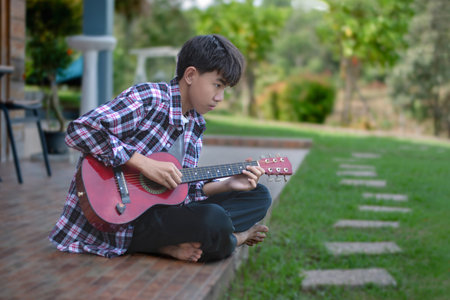 Young asian boy playing guitar in the garden, education concept.の写真素材