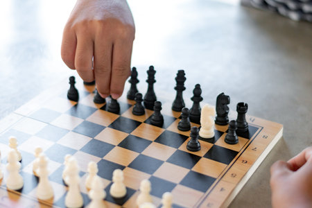 Close up of hand of man playing chess on wooden board with chess pieces.の写真素材