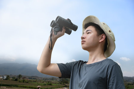 Young asian man with binoculars looking at the landscape.の写真素材