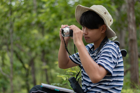 Young asian boy taking photo with camera in the nature park.