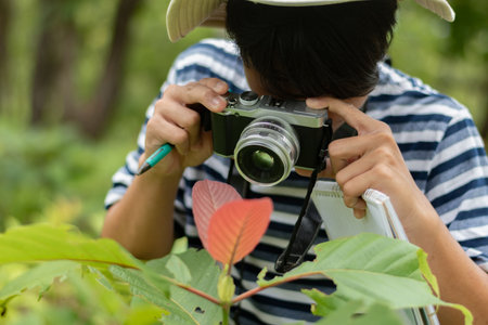 Young man taking a photo with a camera in the park, Thailand.
