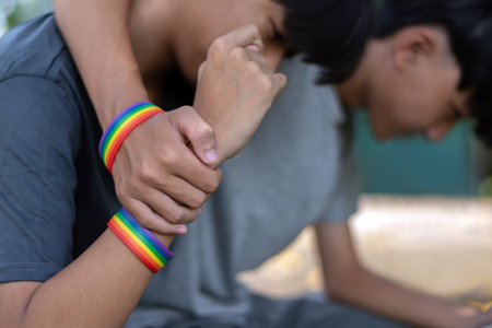 Hands of a boy and a girl with LGBT rainbow wristbandsの写真素材