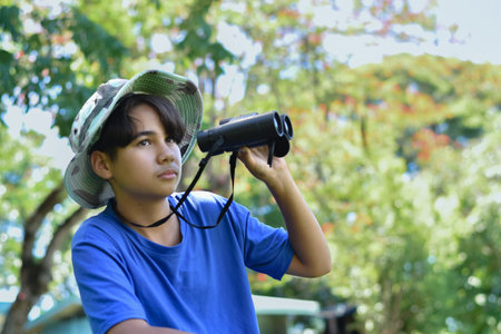 Young asian boy looking through binoculars in the park.の写真素材