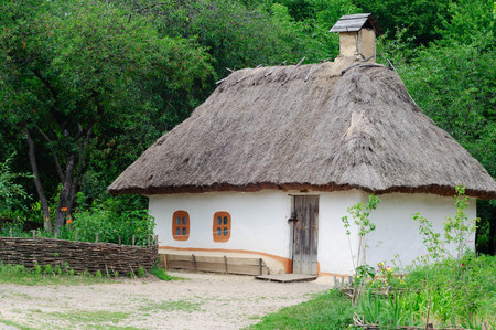 Old wooden house in the Ukrainian village. The traditional housing for the residents of the Ukrainian village. The roof is made of strawの写真素材