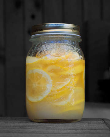 Mason jar glass of homemade lemonade on a rustic wooden background.