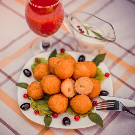 Hot juicy fried cheese balls with sauce on a white plate. Glass of tomato juice.の写真素材