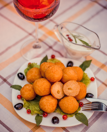 Hot juicy fried cheese balls with sauce on a white plate. Glass of red wine.の写真素材