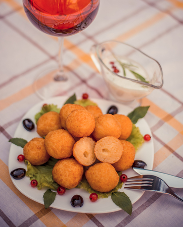 Hot juicy fried cheese balls with sauce on a white plate. Glass of red wine.の写真素材