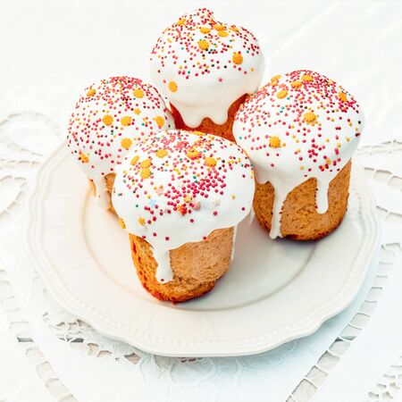 Happy Easter cake with sprinkles on white glaze. Cake on white rustic board, lace cloth. Homemade...