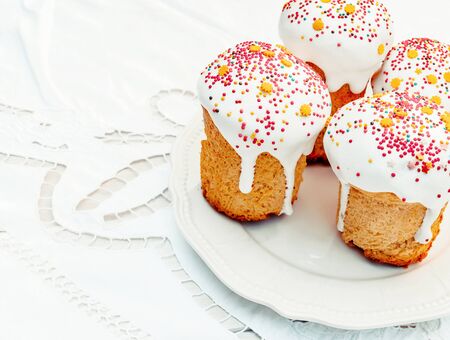 Happy Easter cake with sprinkles on white glaze. Cake on white rustic board, lace cloth. Homemade...