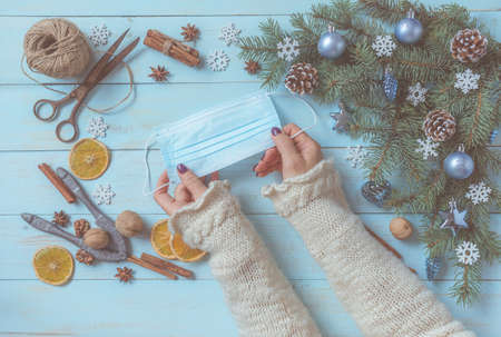 Christmas blue background, spices, woman hands with face mask. Covid-19, coronavirus awareness....