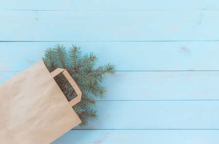 Christmas light blue wooden background, zero waste, corner decoration with paper bag and fir twigs. Flat lay, copy-space.の写真素材