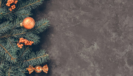 Christmas dark grunge horizontal background, top view. Fir twigs, red golden berries, baubles. Winter holidays, New Year decoration, pine tree branches, snow covered cones, flat lay, copy space.の写真素材