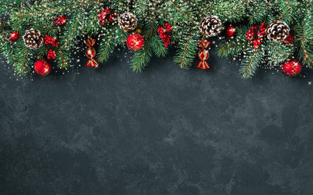Christmas dark grunge horizontal background, top view. Fir twigs, red golden berries, baubles. Winter holidays, New Year decoration, pine tree branches, snow covered cones, flat lay, copy space.の写真素材