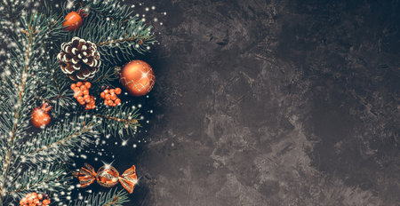 Christmas dark grunge horizontal background, top view. Fir twigs, red golden berries, baubles. Winter holidays, New Year decoration, pine tree branches, snow covered cones, flat lay, copy space.の写真素材