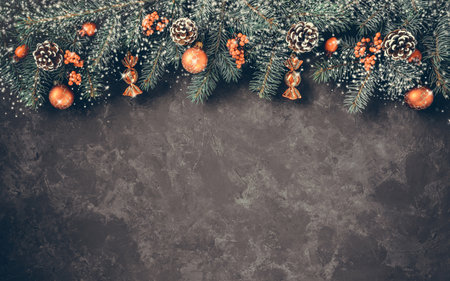 Christmas dark grunge horizontal background, top view. Fir twigs, red golden berries, baubles. Winter holidays, New Year decoration, pine tree branches, snow covered cones, flat lay, copy space.の写真素材