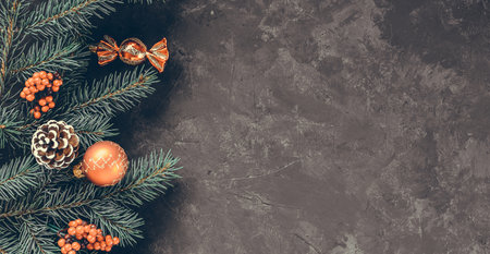 Christmas dark grunge horizontal background, top view. Fir twigs, red golden berries, baubles. Winter holidays, New Year decoration, pine tree branches, snow covered cones, flat lay, copy space.の写真素材