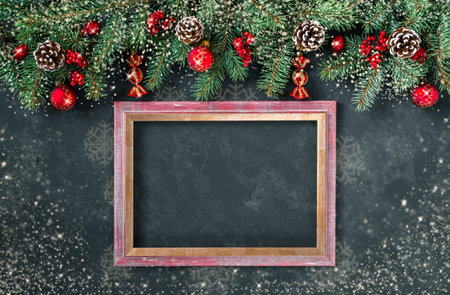 Christmas dark grunge horizontal background with snow, top view. Fir twigs, red golden berries, baubles, frame for wishes. New Year decoration, pine tree branches, snow covered cones, copy space.の写真素材