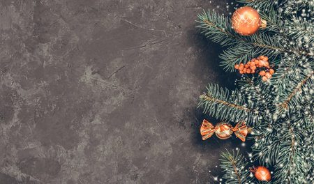 Christmas dark grunge horizontal background, top view. Fir twigs, red golden berries, baubles. Winter holidays, New Year decoration, pine tree branches, snow covered cones, flat lay, copy space.の写真素材
