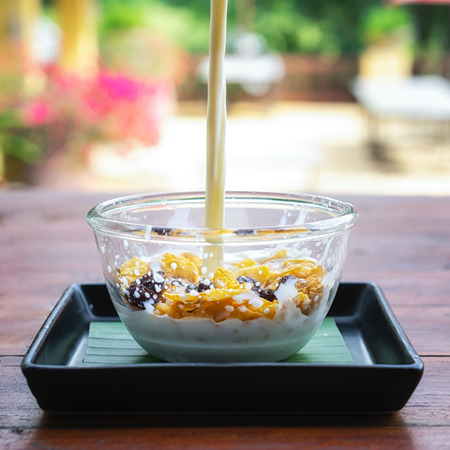 Corn flakes breakfast cereal with milk splash in the cup. Healthy breakfast.