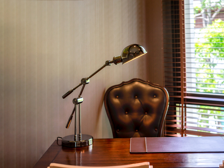 Side view picture of studio workplace with lamp and brown armchair. Designer comfortable work table, home office.の写真素材