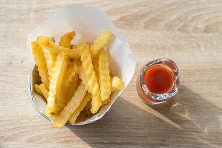French fries with ketchup on the wood table in the restaurant.