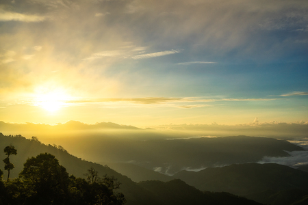 Fog in mountains, fantasy and colorful nature landscape and ray of sunlight through clouds, view from the top view of mountains.の写真素材