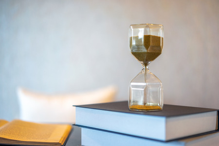 Hourglass and old book with blurred background. Leave copy space for adding text.