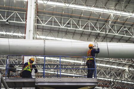 Two workers are installing piping system fabrication & installation in the factory.