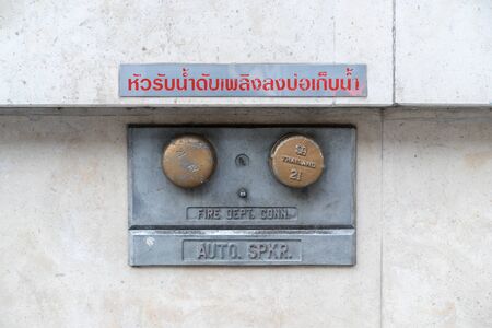 Large fire department connection on cement wall.