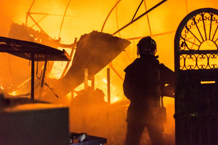 Silhouettes of fireman using water and extinguisher to fighting with fire flame in an emergency situation.の写真素材