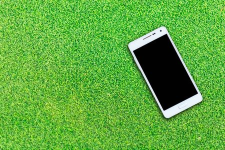 White smart phone with isolated screen on grass backgroundの写真素材