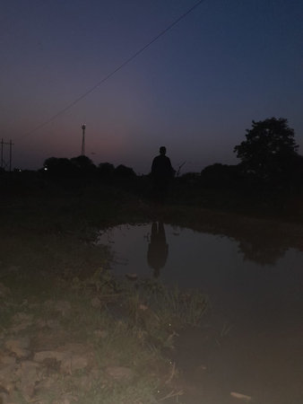 Sunset in the countryside, with a reflection of a man in a puddleの写真素材