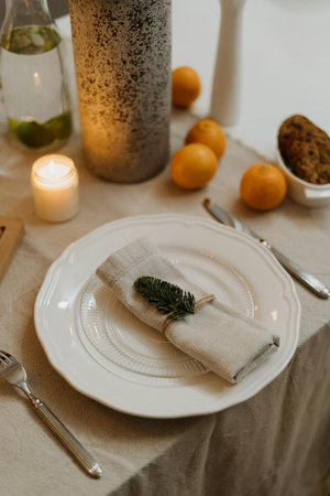 Christmas table setting with white plates, silverware, napkin and candles