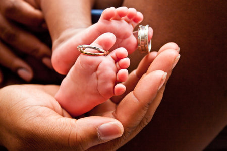 Newborn baby feet in the hands of a mother and father.の写真素材