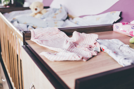 baby clothes on the bed in the bedroom, soft focus background.
