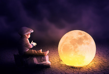 Little boy sitting on cracked ground and looking at moon.の写真素材