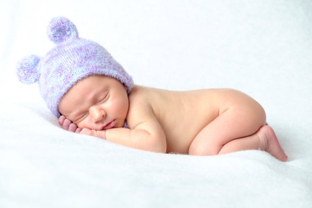 Newborn baby sleeping in a knitted hat on a white backgroundの写真素材