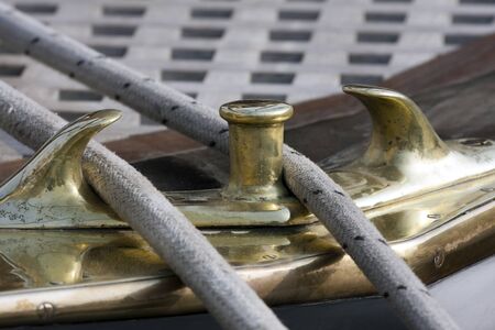 Vintage brass mooring cleat with a rope to secure a yacht to the pier.