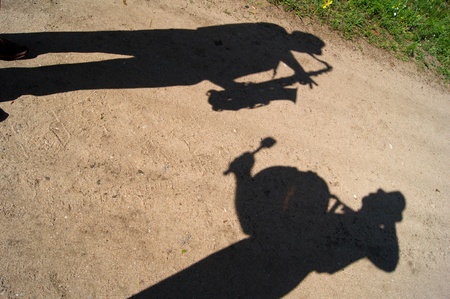 Shadows of two musicians on a sandy road