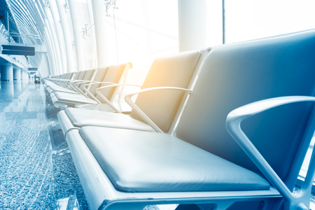Row of leather chairs in international airport terminal at window background.のeditorial素材