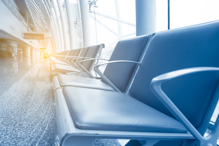 Row of leather chairs in international airport terminal at window background.のeditorial素材