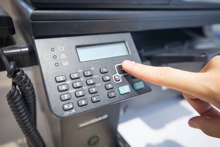 Man holding finger on start button of laser printer